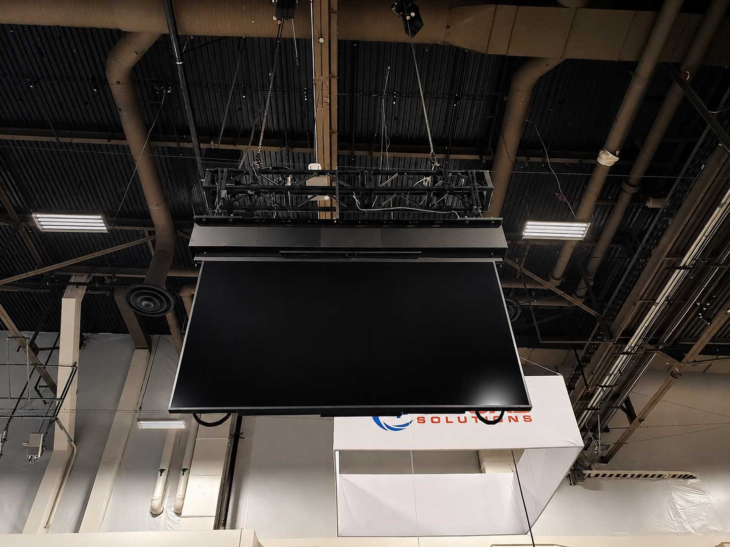 Hung above RPV's product-packed booth at Infocomm 2026 is an impressive, motorized lift that raises and lowers a massive 110” LG Flat Panel with ease.